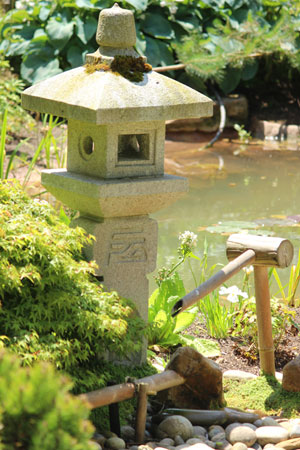 Close-up view of the deer scarer water feature and adjacent 'Oribe' granite lantern
